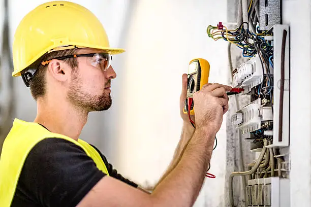 Electrician repairing overheated breaker panel in older Asbury Park home basement